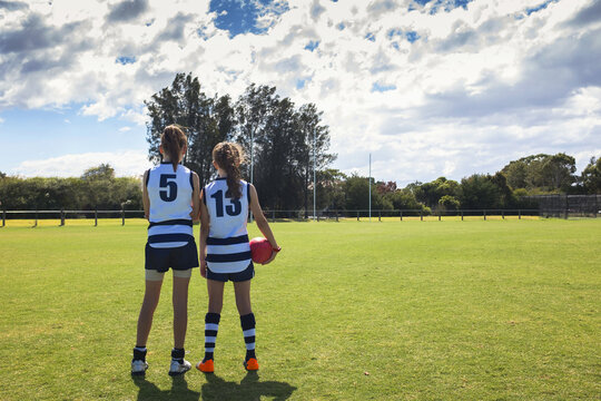 Two junior players standing pitch-side with the footy