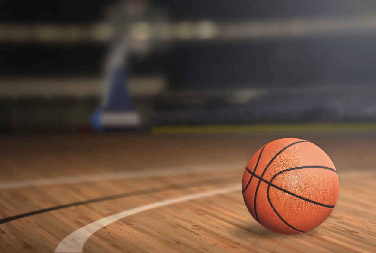 Basketball resting on the court under stadium lights