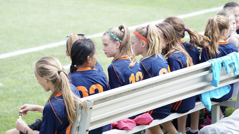 Junior sports team watching a match together from the bench