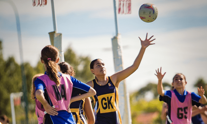 Netball player reaching for the ball mid-game